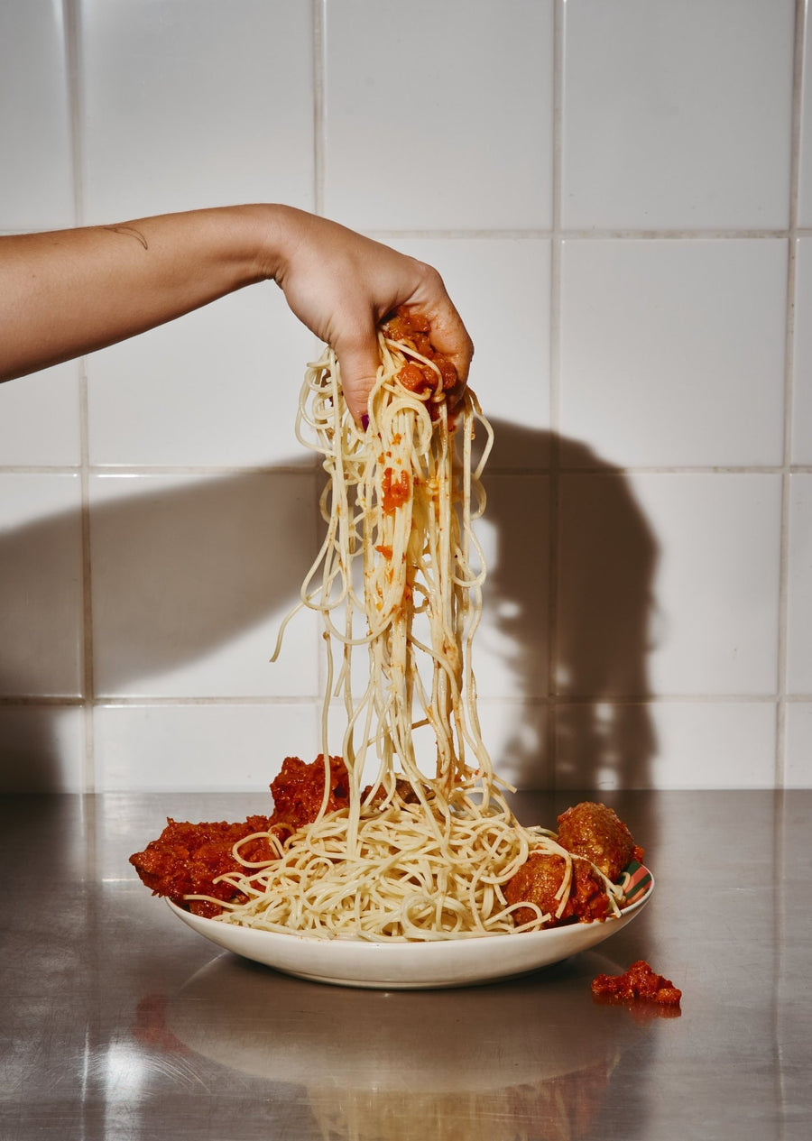 Une main tire des spaghettis d’une assiette FUELED