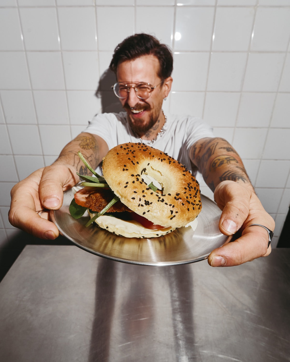 Un cuisinier FUELED tend une assiette avec un bagel, en souriant.